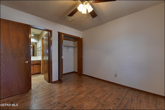 unfurnished bedroom with a textured ceiling, a closet, wood finished floors, and visible vents