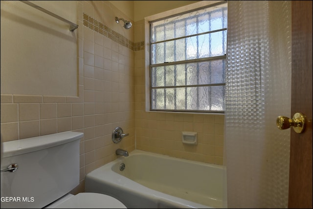 bathroom featuring a wealth of natural light, tile walls, bathing tub / shower combination, and toilet