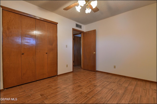 unfurnished bedroom featuring baseboards, visible vents, light wood-style flooring, a textured ceiling, and a closet