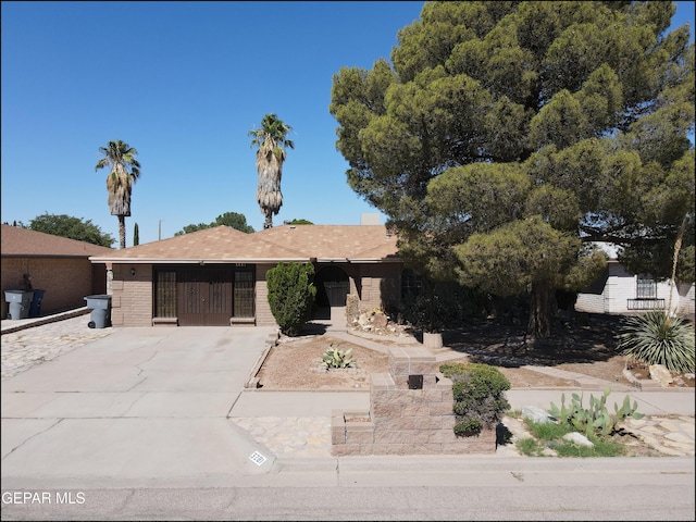 view of front of home featuring a gate, brick siding, and driveway