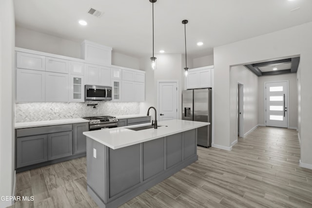 kitchen with light hardwood / wood-style flooring, backsplash, white cabinets, appliances with stainless steel finishes, and sink