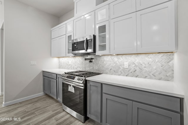 kitchen with white cabinetry, stainless steel appliances, gray cabinets, and tasteful backsplash