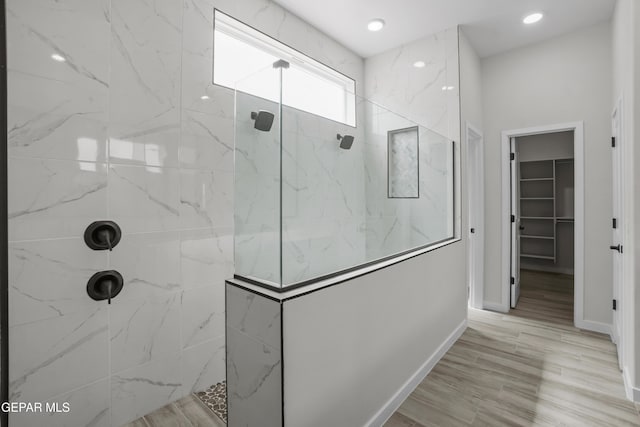 full bathroom with a walk in closet, baseboards, a marble finish shower, and recessed lighting