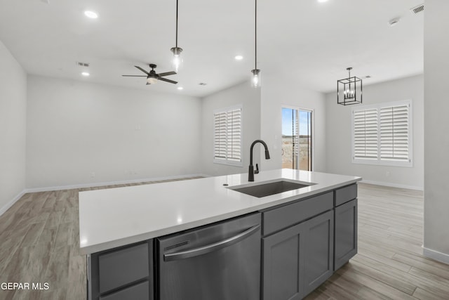 kitchen with light countertops, stainless steel dishwasher, open floor plan, a kitchen island with sink, and a sink