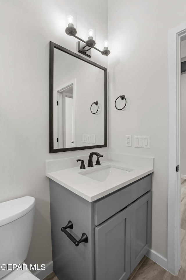 bathroom with toilet, baseboards, and vanity