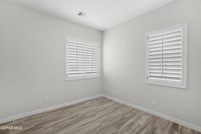 unfurnished room with light wood-type flooring, visible vents, and baseboards