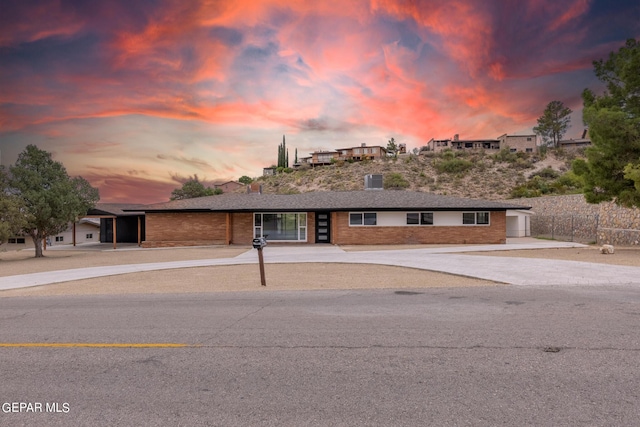 ranch-style house with brick siding, concrete driveway, and fence