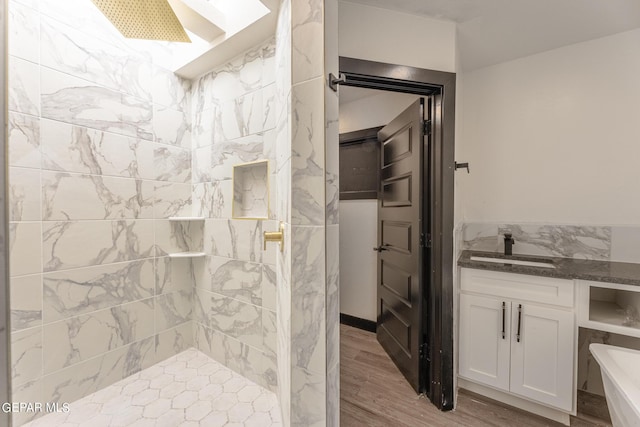 full bathroom featuring wood finished floors, a tile shower, and a sink