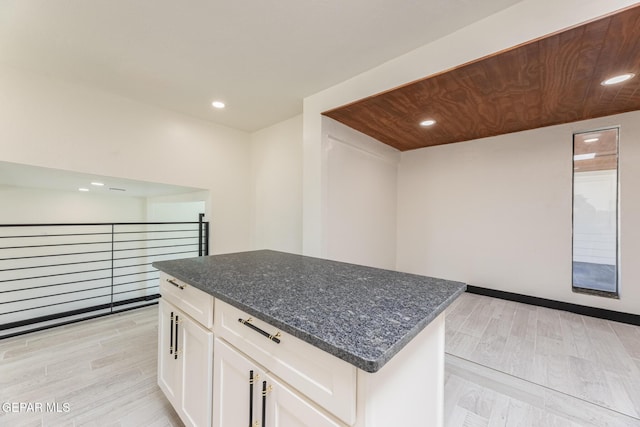 kitchen featuring recessed lighting, white cabinets, dark stone counters, and light wood-type flooring