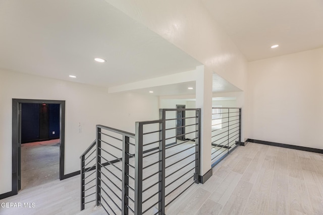 hall featuring an upstairs landing, recessed lighting, light wood-type flooring, and baseboards