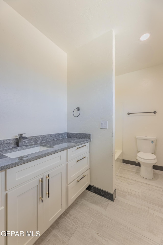 full bath with baseboards, toilet, and vanity