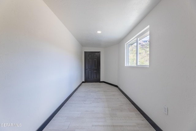 hall featuring light wood-type flooring and baseboards