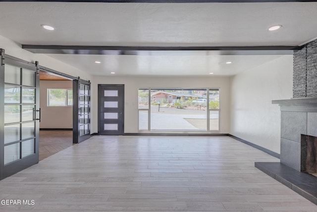 foyer entrance featuring a barn door, beamed ceiling, and a healthy amount of sunlight