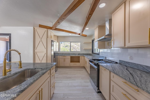 kitchen featuring backsplash, wall chimney range hood, beamed ceiling, gas range oven, and a sink