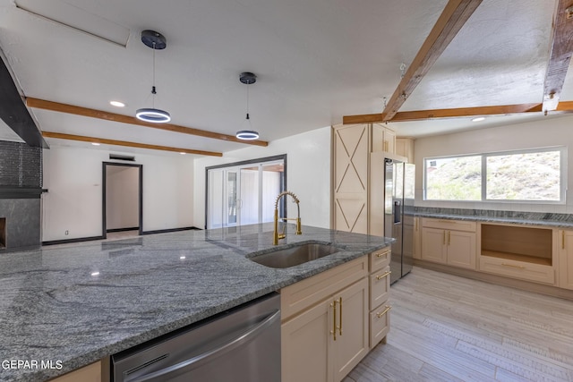 kitchen with light wood-type flooring, beam ceiling, a sink, dark stone countertops, and stainless steel appliances