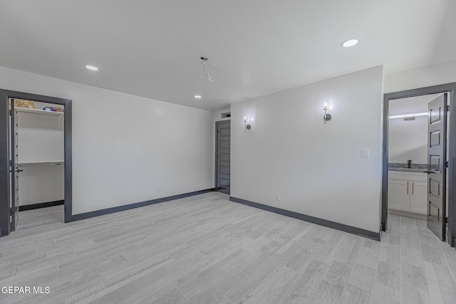 spare room featuring recessed lighting, baseboards, and light wood finished floors