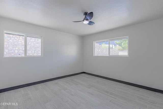 spare room with ceiling fan, light wood-style floors, and baseboards