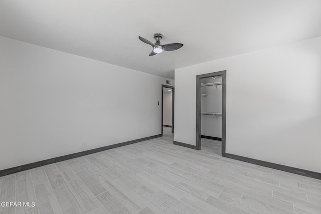 spare room with a ceiling fan, light wood-type flooring, and baseboards