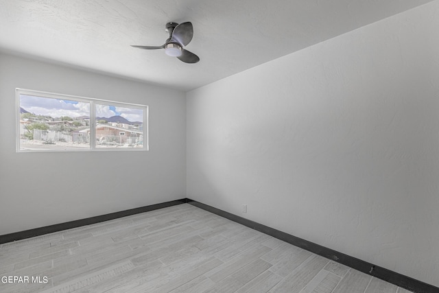 empty room with baseboards, light wood-style floors, and a ceiling fan