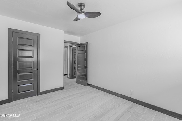 empty room featuring a ceiling fan, light wood-style floors, and baseboards