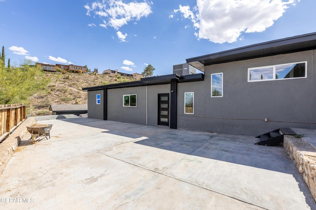 rear view of property featuring stucco siding, fence, and a patio area