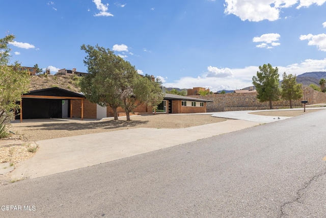 ranch-style house featuring a mountain view, brick siding, and concrete driveway