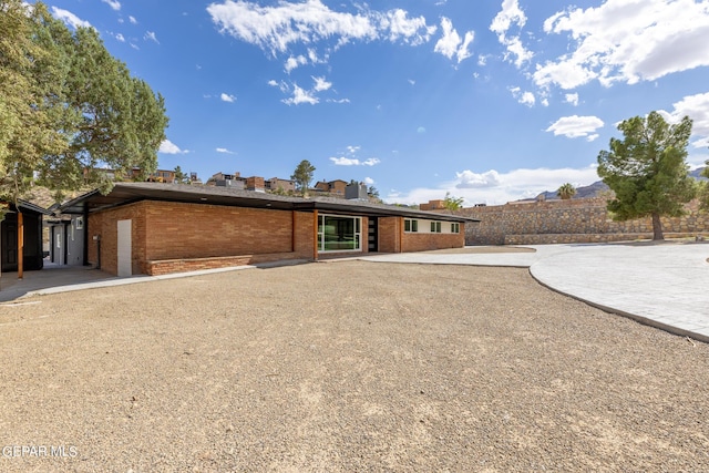 rear view of property featuring gravel driveway and brick siding