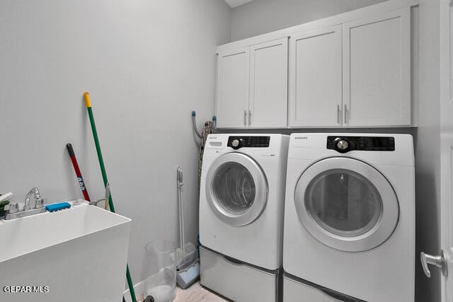 laundry area featuring independent washer and dryer, sink, and cabinets