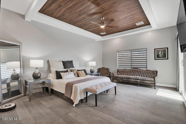 bedroom with ceiling fan, a raised ceiling, wood ceiling, and wood-type flooring