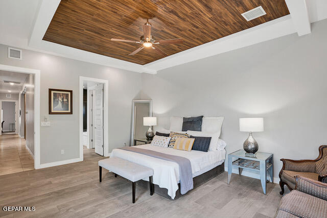 tiled bedroom featuring ceiling fan, a raised ceiling, and wooden ceiling