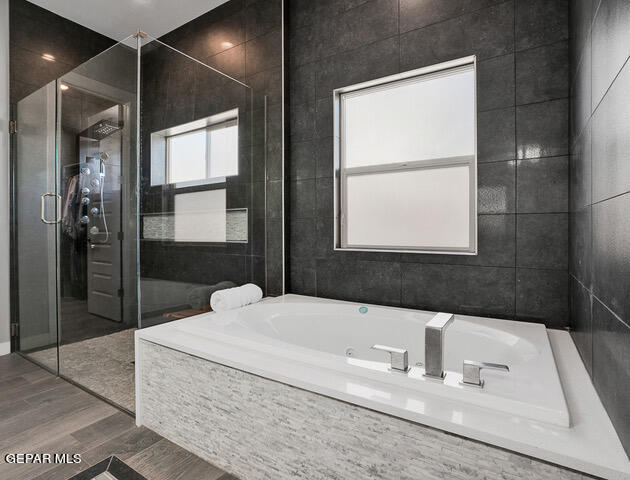 bathroom featuring tile walls, independent shower and bath, and wood-type flooring