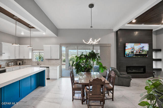 kitchen featuring hanging light fixtures, stainless steel dishwasher, a large fireplace, and light tile patterned floors