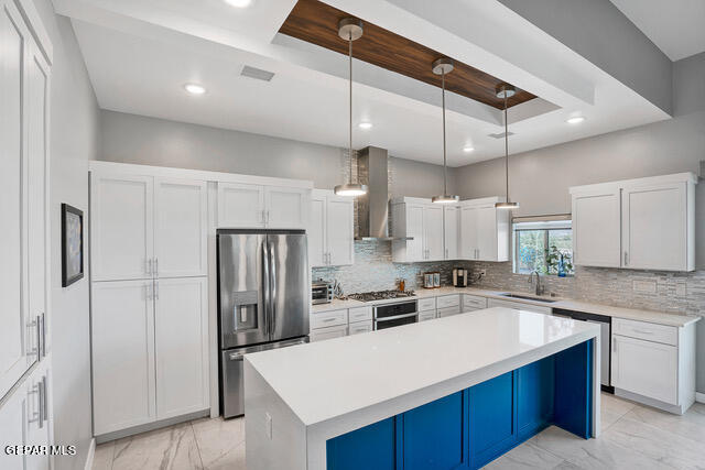 kitchen featuring stainless steel appliances, wall chimney exhaust hood, tasteful backsplash, and white cabinets