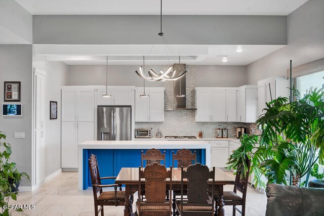 kitchen featuring backsplash, white cabinetry, decorative light fixtures, stainless steel fridge, and light tile patterned flooring