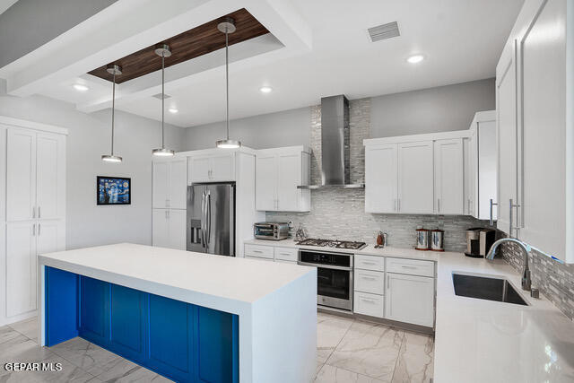 kitchen featuring appliances with stainless steel finishes, sink, wall chimney exhaust hood, and white cabinets