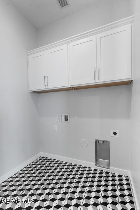 clothes washing area with hookup for an electric dryer, tile patterned flooring, cabinets, and washer hookup