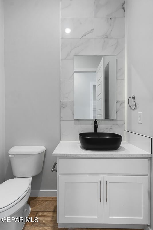 bathroom with hardwood / wood-style flooring, toilet, and vanity