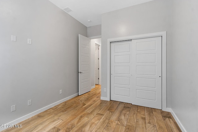 unfurnished bedroom with a closet and light hardwood / wood-style floors