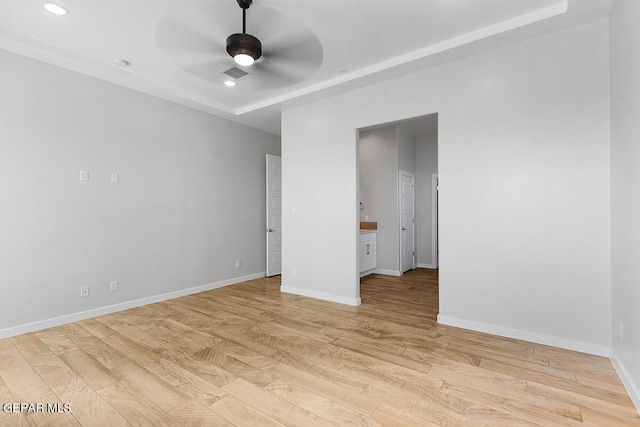 unfurnished bedroom with ceiling fan, light hardwood / wood-style floors, and a raised ceiling