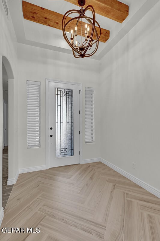 entrance foyer with light parquet floors, a tray ceiling, a notable chandelier, and beam ceiling