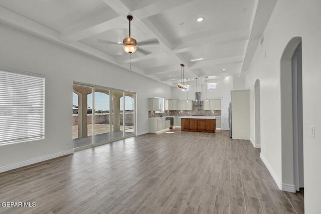 unfurnished living room featuring light hardwood / wood-style flooring, ceiling fan, coffered ceiling, and beamed ceiling