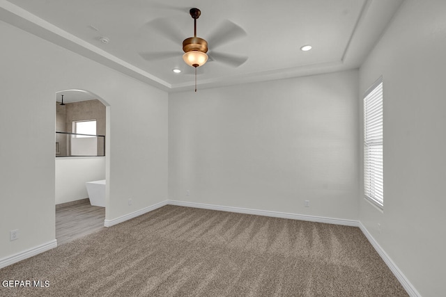 empty room with a healthy amount of sunlight, ceiling fan, and light carpet