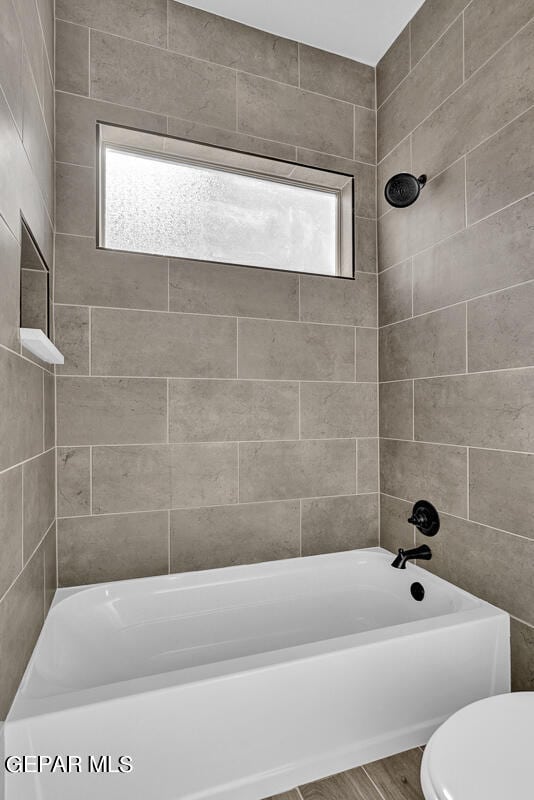 bathroom with plenty of natural light, toilet, wood-type flooring, and tiled shower / bath