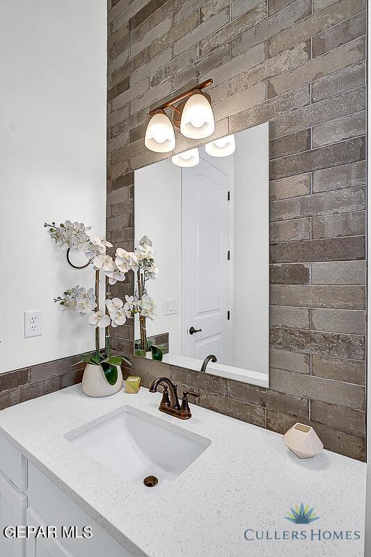 bathroom with backsplash, vanity, and brick wall