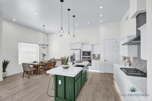 kitchen featuring backsplash, an island with sink, green cabinetry, white cabinetry, and appliances with stainless steel finishes