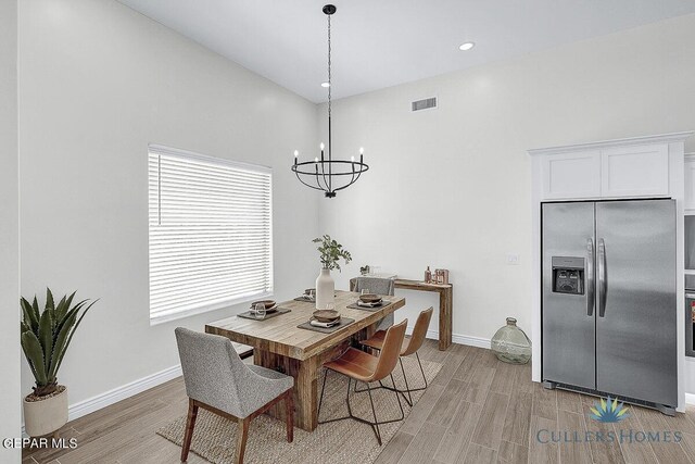 dining space featuring light hardwood / wood-style floors and a chandelier