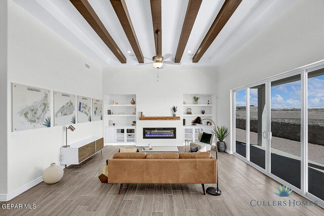 living room featuring ceiling fan, beam ceiling, hardwood / wood-style floors, and a high ceiling