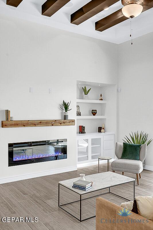 living room featuring beamed ceiling, ceiling fan, and hardwood / wood-style flooring