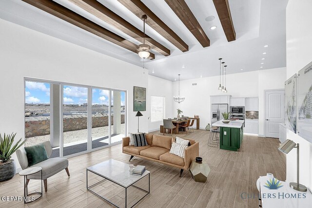 living room with a towering ceiling, beam ceiling, and light hardwood / wood-style floors