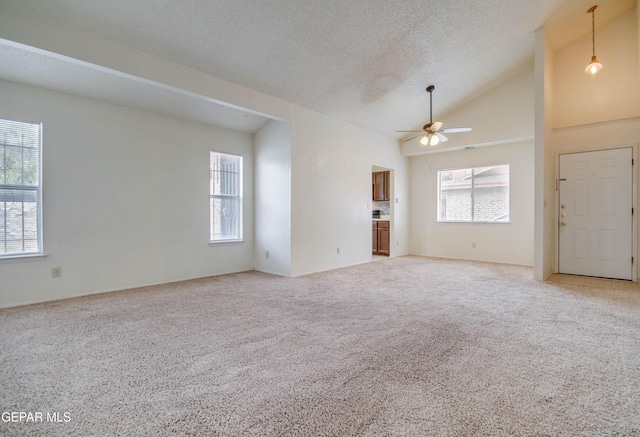 unfurnished living room with a textured ceiling, light carpet, high vaulted ceiling, and ceiling fan